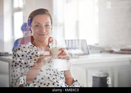 Portrait of smiling businesswoman drinking coffee in office Banque D'Images