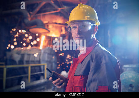 Portrait confiant, steelworker sérieux avec walkie-talkie dans l'aciérie Banque D'Images