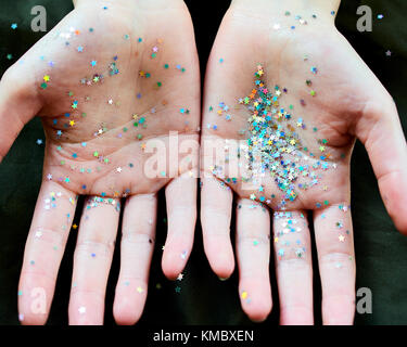 Confettis étoiles scintiller sur les mains Banque D'Images