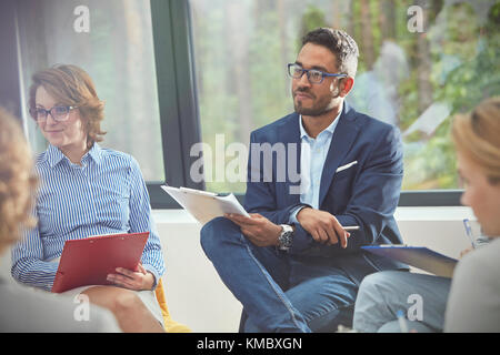 L'homme attentif à l'écoute du presse-papiers dans la thérapie de groupe session Banque D'Images