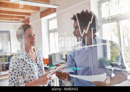 Les gens d'affaires avec l'examen des écritures sur verre graphique in office Banque D'Images