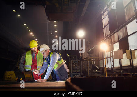 Steelworkers utilisant un ordinateur portable dans une aciérie Banque D'Images