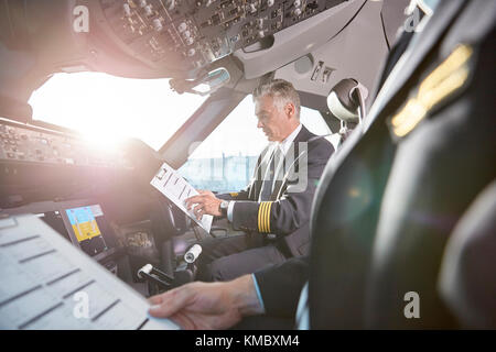 Pilotes mâles avec presse-papiers se préparant dans le cockpit d'avion Banque D'Images