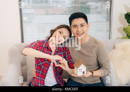 Happy smiling couple holding un modèle maison. accueil concept d'assurance Banque D'Images