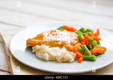 Poulet cuit au four en sauce avec une purée de pommes de terre et légumes sur fond de bois rustique Banque D'Images