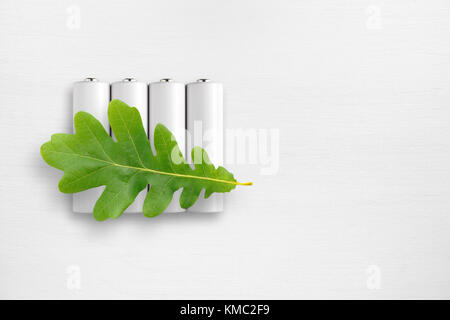 Batteries et feuille de chêne vert sur le tableau blanc. L'énergie écologique concept. Banque D'Images