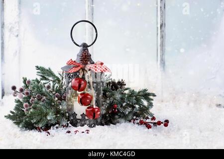 Ancienne lanterne de Noël avec des branches d'arbre de pin assis sur un rebord de fenêtre enneigée. Banque D'Images