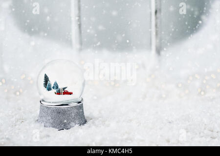 Silver snow globe avec un camion jouet un arbre de Noël. snow globe est assis à l'extérieur, sur le rebord d'une vieille fenêtre en bois dans la neige. Banque D'Images