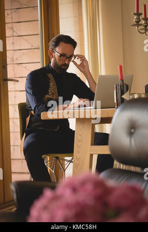 Homme bien habillé en utilisant un ordinateur portable sur la table à manger Banque D'Images