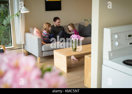 Père et filles utilisant une tablette numérique dans le salon Banque D'Images