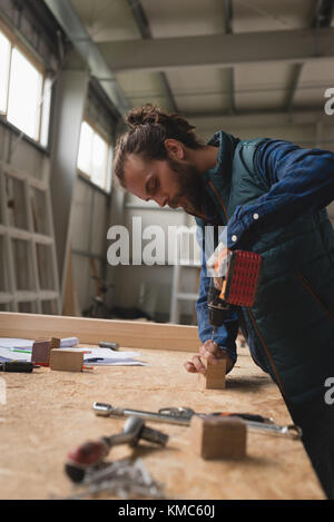 Carpenter faire trou dans un bloc en bois avec des armes à feu à vis Banque D'Images