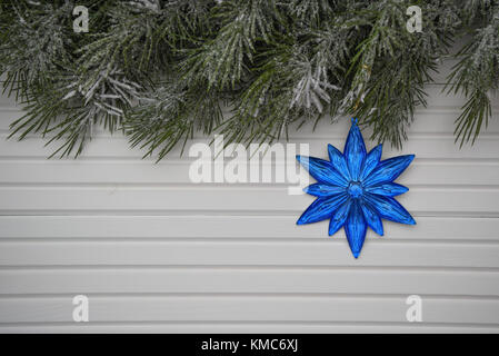 Photographie image de Noël avec arbre vert garland arrosé avec de la neige et des étoiles bleu vif ou décoration florale un arrière-plan blanc bois naturel Banque D'Images