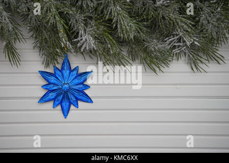 Photographie image de Noël avec arbre vert garland arrosé avec de la neige et des étoiles bleu vif ou décoration florale un arrière-plan blanc bois naturel Banque D'Images