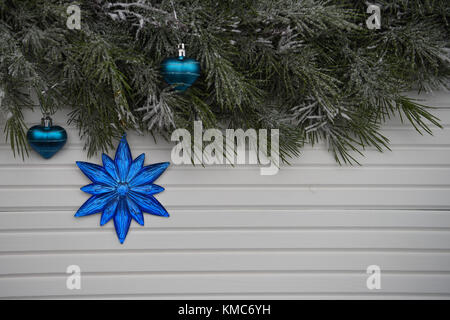 Photographie image de Noël avec arbre vert garland arrosé avec de la neige et des étoiles bleu vif ou décoration florale un arrière-plan blanc bois naturel Banque D'Images