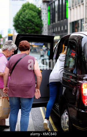 Les femmes d'entrer dans un taxi noir de Londres, Angleterre, RU Banque D'Images