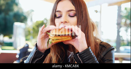 Teenage girl eating a hamburger Banque D'Images