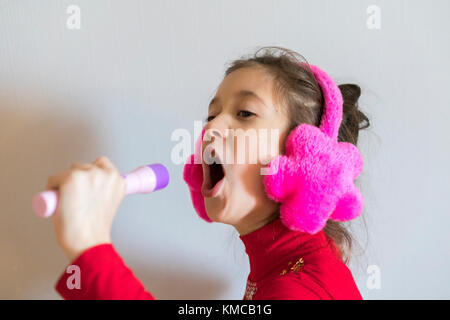 8 ans, fille d'écouteurs chanter Banque D'Images