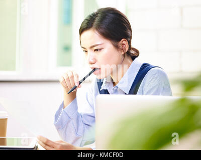 Young Asian woman cadre d'entreprise l'analyse d'un rapport dans un bureau moderne. Banque D'Images