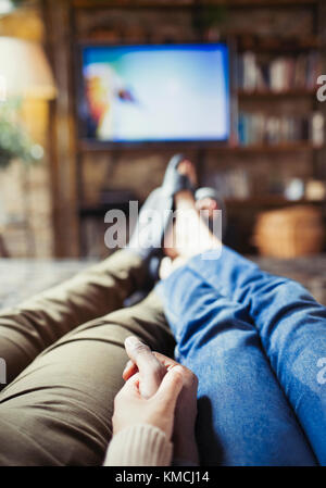 Perspective personnelle couple affectueux tenant les mains regardant la télévision dans la vie chambre Banque D'Images