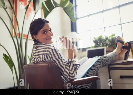 Portrait d'une femme d'affaires confiante qui travaille, examine les documents avec les pieds vers le haut sur le bureau Banque D'Images