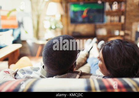 Un jeune couple se détendant, regardant la télévision sur le canapé du salon Banque D'Images