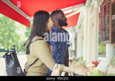 Jeune couple à la recherche de produits, en regardant les prix sur le marché extérieur Banque D'Images