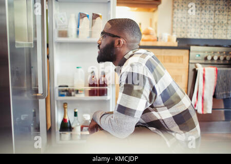 Homme affamé en scrutant réfrigérateur dans la cuisine Banque D'Images