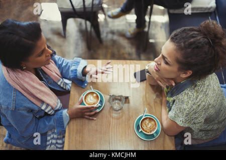 Les jeunes femmes amis parlent et boivent des cappuccinos à la table du café Banque D'Images
