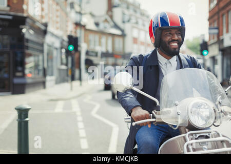 Jeune homme d'affaires souriant dans un casque de scooter de moteur sur urbain rue Banque D'Images