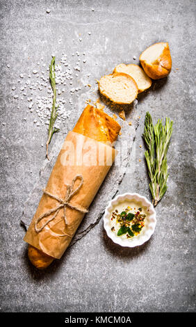 Le ciabatta enveloppé dans du papier avec le romarin et l'huile. sur la table de pierre. Vue de dessus Banque D'Images