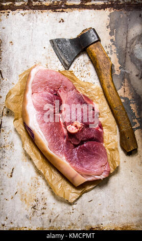 Un gros morceau de viande de porc cru avec une hache. sur fond rustique. Vue de dessus Banque D'Images