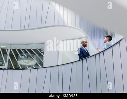 Les hommes d'affaires parlent sur un balcon de bureau moderne et architectural Banque D'Images