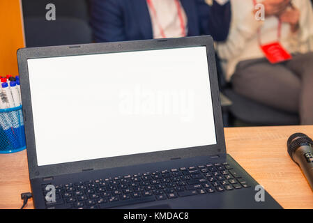 Close up portable avec écran vide et micros sur la table dans la salle de conférence pendant l'événement. participants floue sur l'arrière-plan d'affaires, concept. Banque D'Images