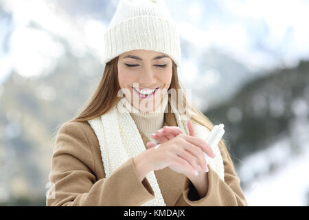 Vue avant portrait d'une femme heureuse application de crème hydratante pour hydrater les mains avec une montagne en arrière-plan Banque D'Images