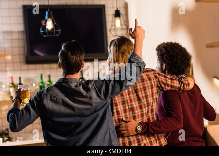 Les amis de regarder la télévision en bar Banque D'Images