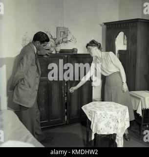 Années 1950, historiques, bienvenue à la Grande-Bretagne, une logeuse montre un homme nouvellement arrivés à la Grande-Bretagne d'immigrants de la Communauté sa chambre meublé ou logement, Londres, Angleterre, Royaume-Uni. Banque D'Images