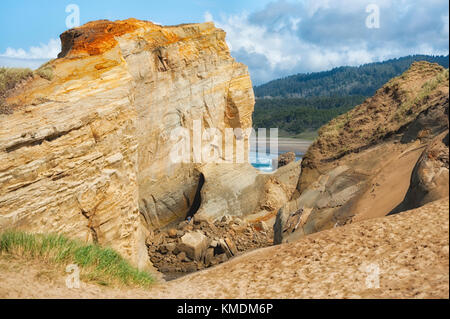 Pacific City, Oregon, USA - 8 Avril 2015 : Effondrement,imposants clifs de grès à Cape Kiwanda dawf un homme explorer c'est dangereux à base de Pacifi que Banque D'Images