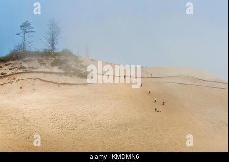 Les vents soufflent de la mer autour de sable et de tourisme les vacanciers l'ascension de la grande dune de sable de Cape Kiwanda dans Pacific City sur la côte de l'Oregon. Banque D'Images