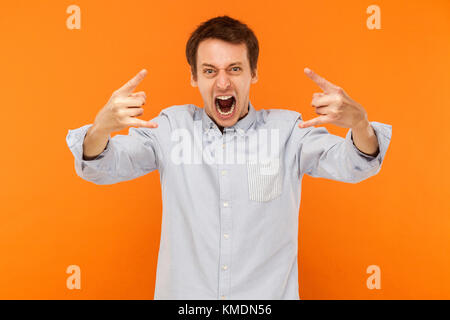 Rock and Roll ! Homme expressif montrant rock main à caméra et crier. Fond orange, Studio shot Banque D'Images