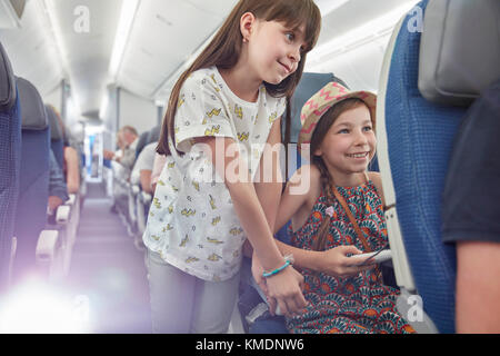 Sœurs Girl playing video game on airplane Banque D'Images