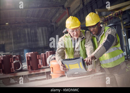 Steelworkers utilisant un ordinateur portable dans une aciérie Banque D'Images