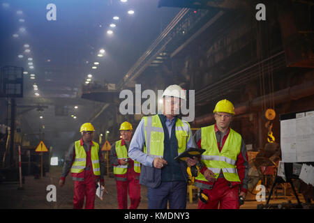 Le superviseur et les travailleurs de la sidérurgie marchent et parlent dans l'aciérie Banque D'Images