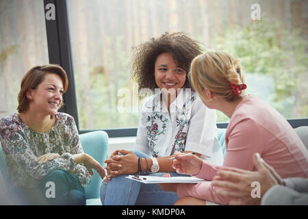 Femmes souriantes parlant en séance de thérapie de groupe Banque D'Images