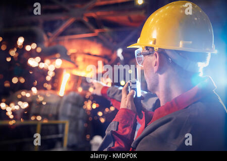 Steelworker parlant, en utilisant walkie-talkie dans l'aciérie Banque D'Images