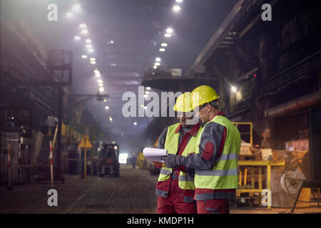 Steelworkers avec presse-papiers dans l'aciérie Banque D'Images