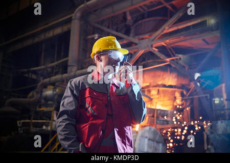 Steelworker parlant, en utilisant walkie-talkie dans l'aciérie Banque D'Images