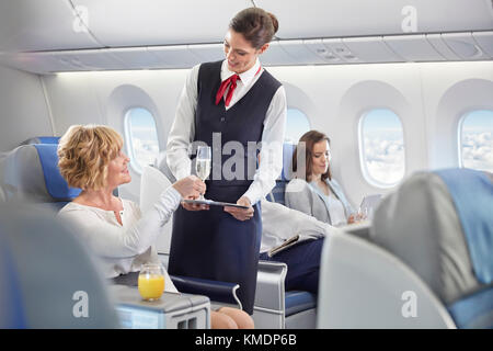 Un employé de bord servant du champagne à une femme en première classe avion Banque D'Images