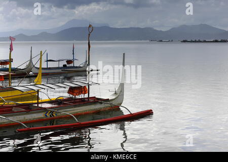 Amarré à l'embarcadère des bateaux-pompe en pirogues à caldera taal lake sous ciel nuageux en attente de passagers touristiques pour les transporter à l'intérieur du volcan Taal Banque D'Images