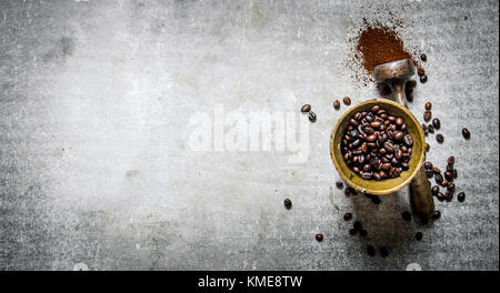 Les grains de café torréfiés dans un mortier avec pilon. sur un fond en pierre. Banque D'Images