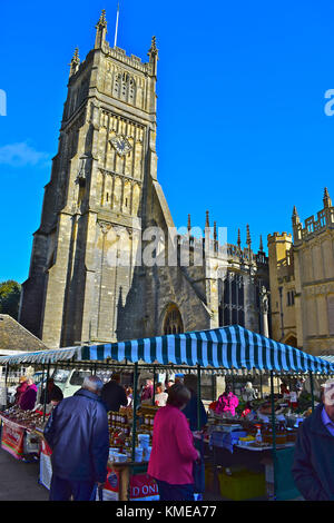 Marché du samedi matin dans le centre-ville de Cirencester dans les Cotswolds, en Angleterre. L'église est l'église paroissiale de St Jean le Baptiste. Banque D'Images